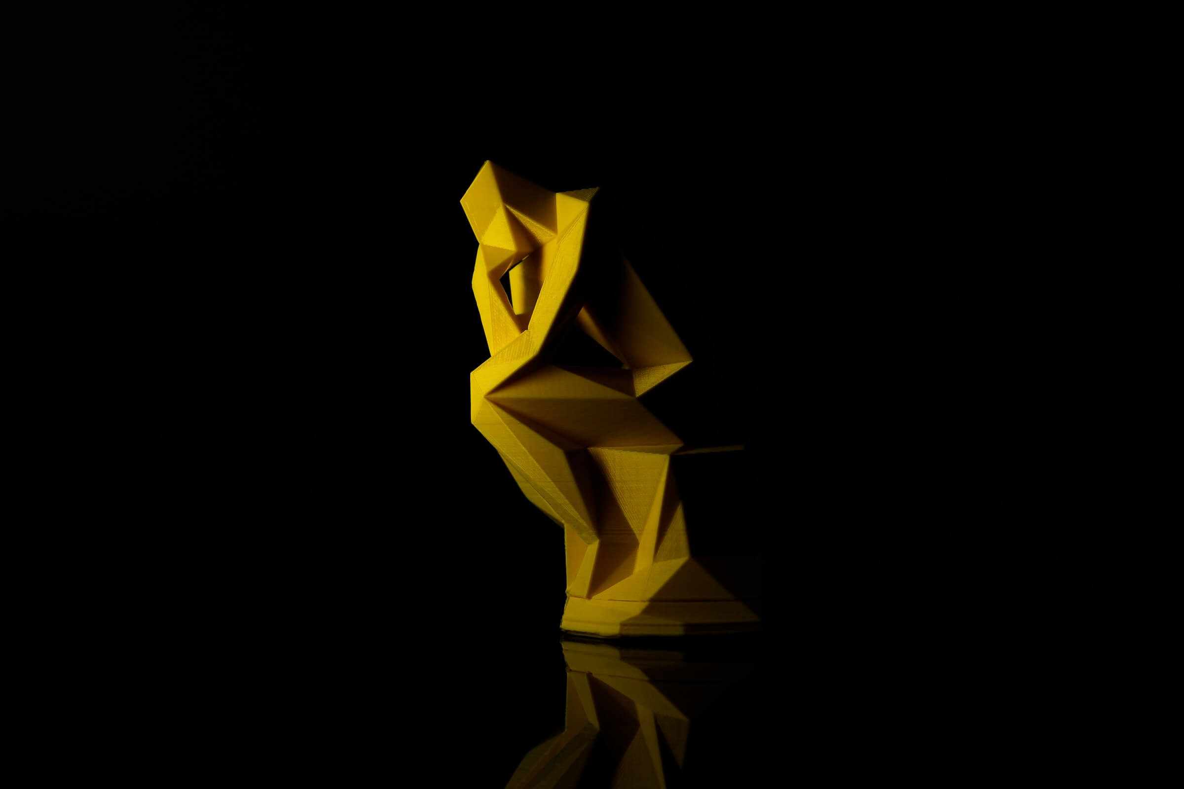 TheThinkerInLowPoly3DPrintedPartsViniciusAmnxAmanoJuly2021 Yellow Sculptural Model of Man with Chin on Hand Against Black Background